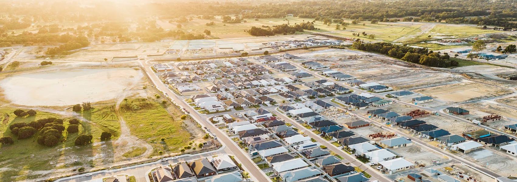 Aerial view of a housing estate spreading across former farmland at sunset