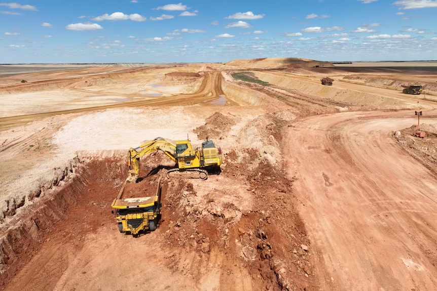 Mining machinery excavating a pit cut into cropping country